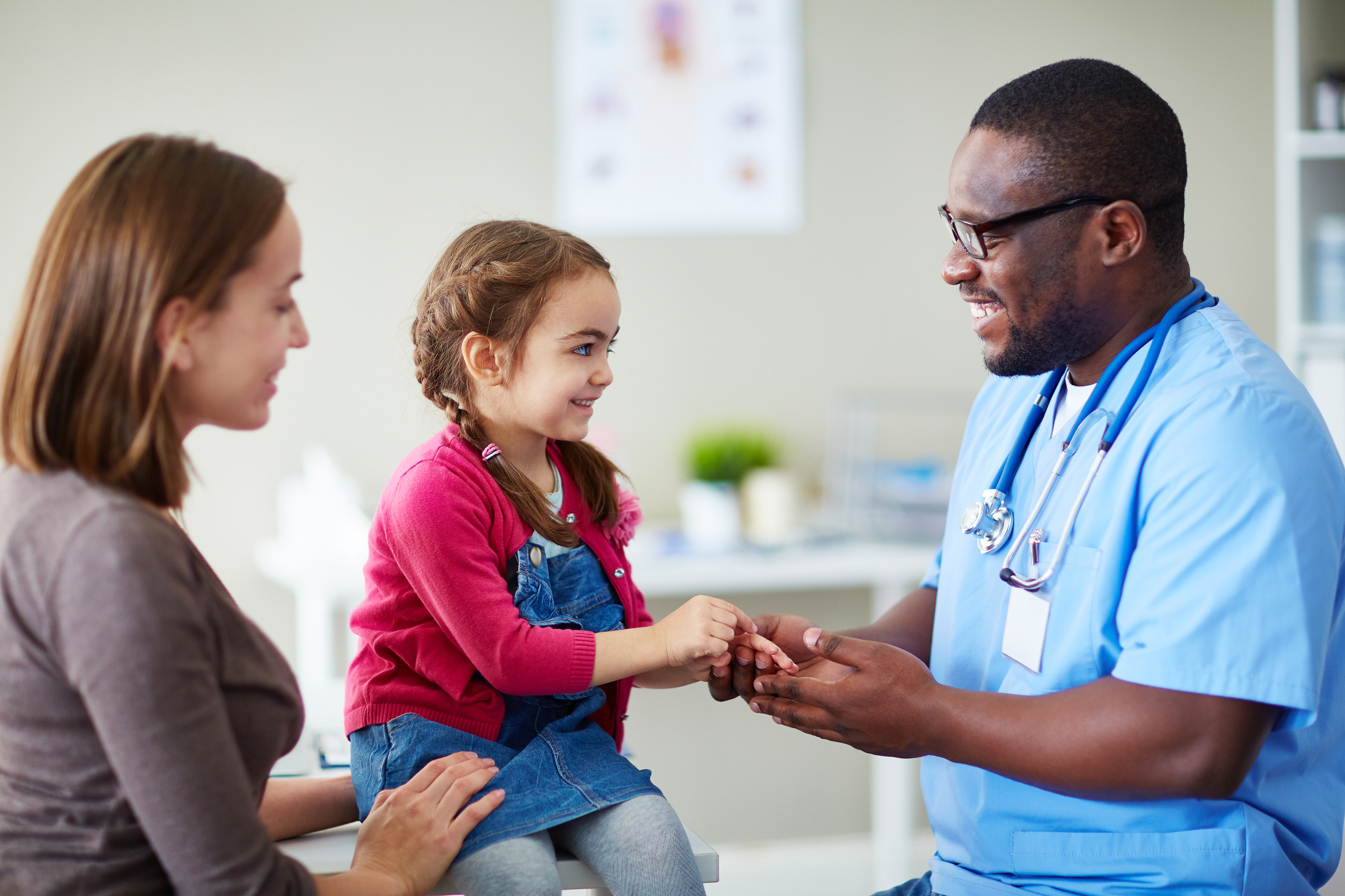 a child and parent looking happy with a medical provider in provider's office